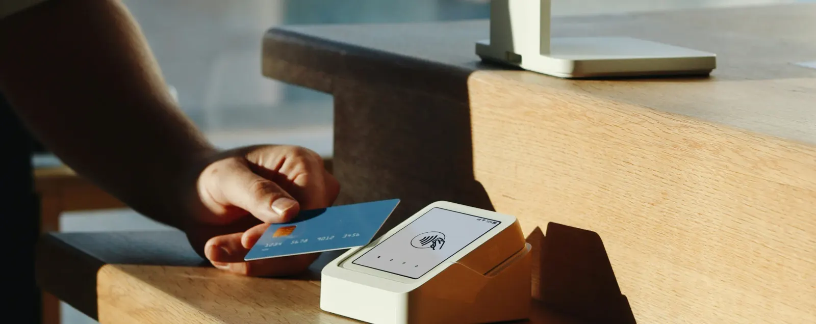 Een gast houdt een kaart tegen een Paybyrd-terminal bij de receptie